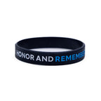A black rubber bracelet with the inscriptions 'HONOR AND REMEMBER' and '9/11 MEMORIAL' in white and blue letters.