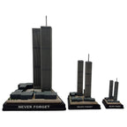A model of the three sizes available of the Twin Towers, with the base label 'NEVER FORGET', in black, gray, and brown colors.