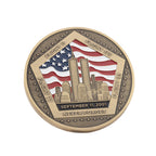 A round commemorative coin featuring the September 11, 2001 attacks, with the Twin Towers, an American flag, and the words 'Flight 11', 'Flight 175', 'Flight 93', 'Flight 77' and 'Never Forget' on a white background.