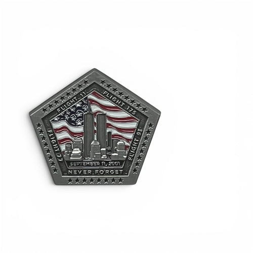 A pentagonal commemorative pin in a dark matte silver finish, featuring an American flag and the New York City skyline with the towers. The flight numbers and  text reading 'SEPT 11 2001', and 'NEVER FORGET' is engraved around the border.