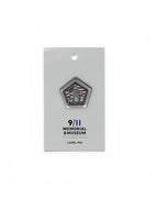A pentagonal lapel pin featuring the 9/11 Memorial & Museum logo, mounted on a white display card against a white background.