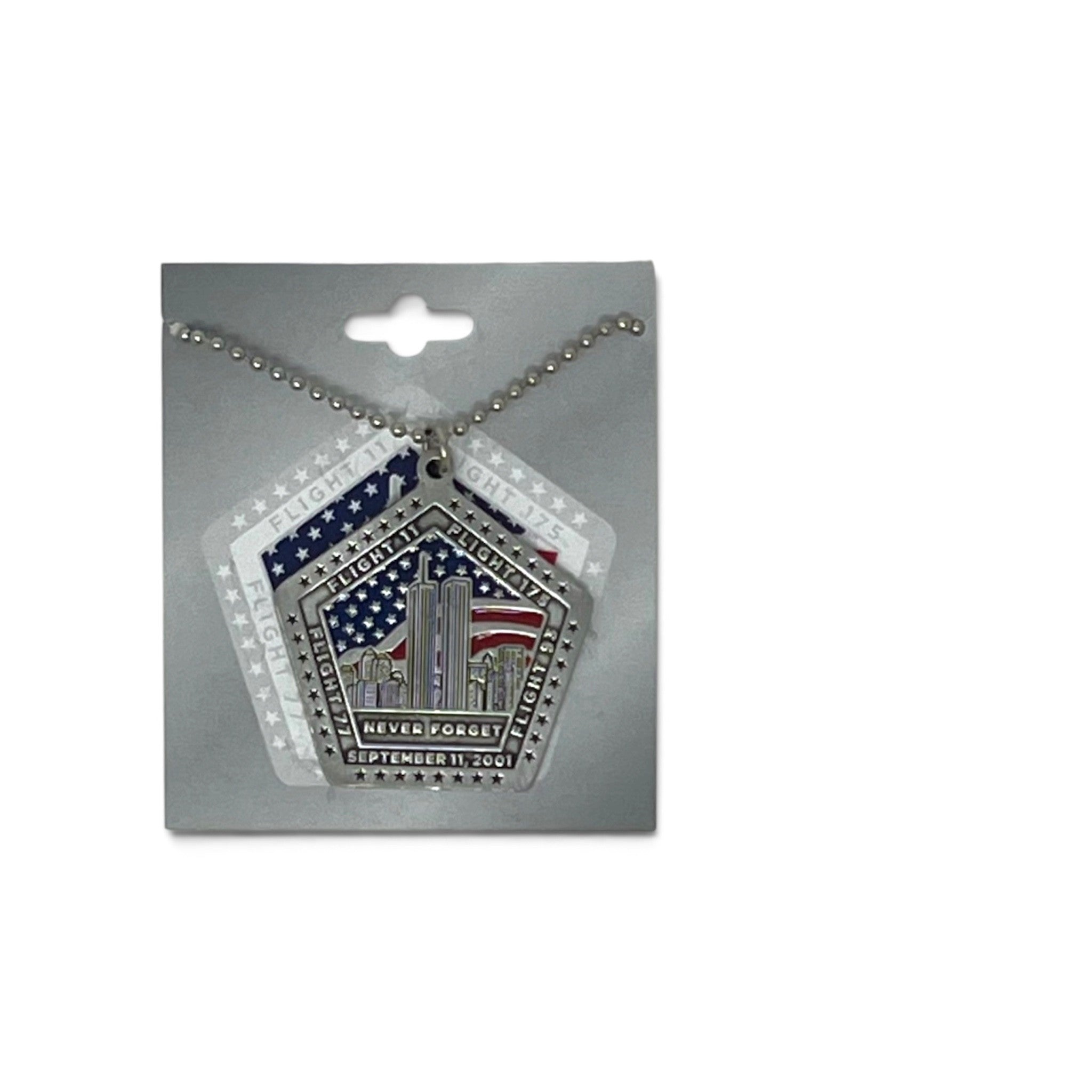 A silver-toned 9/11 memorial pendant necklace on a ball chain, displayed on a gray retail backing card. The pendant features a pentagonal design with the Twin Towers, stars, and red, white, and blue American flag details, plus the text 'NEVER FORGET' and 'SEPTEMBER 11, 2001'.