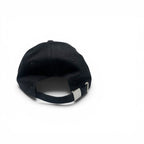 A black baseball cap shown from the back, featuring a black fabric crown, matching black eyelets, and an adjustable black strap with a silver metal slider, set against a plain white background.