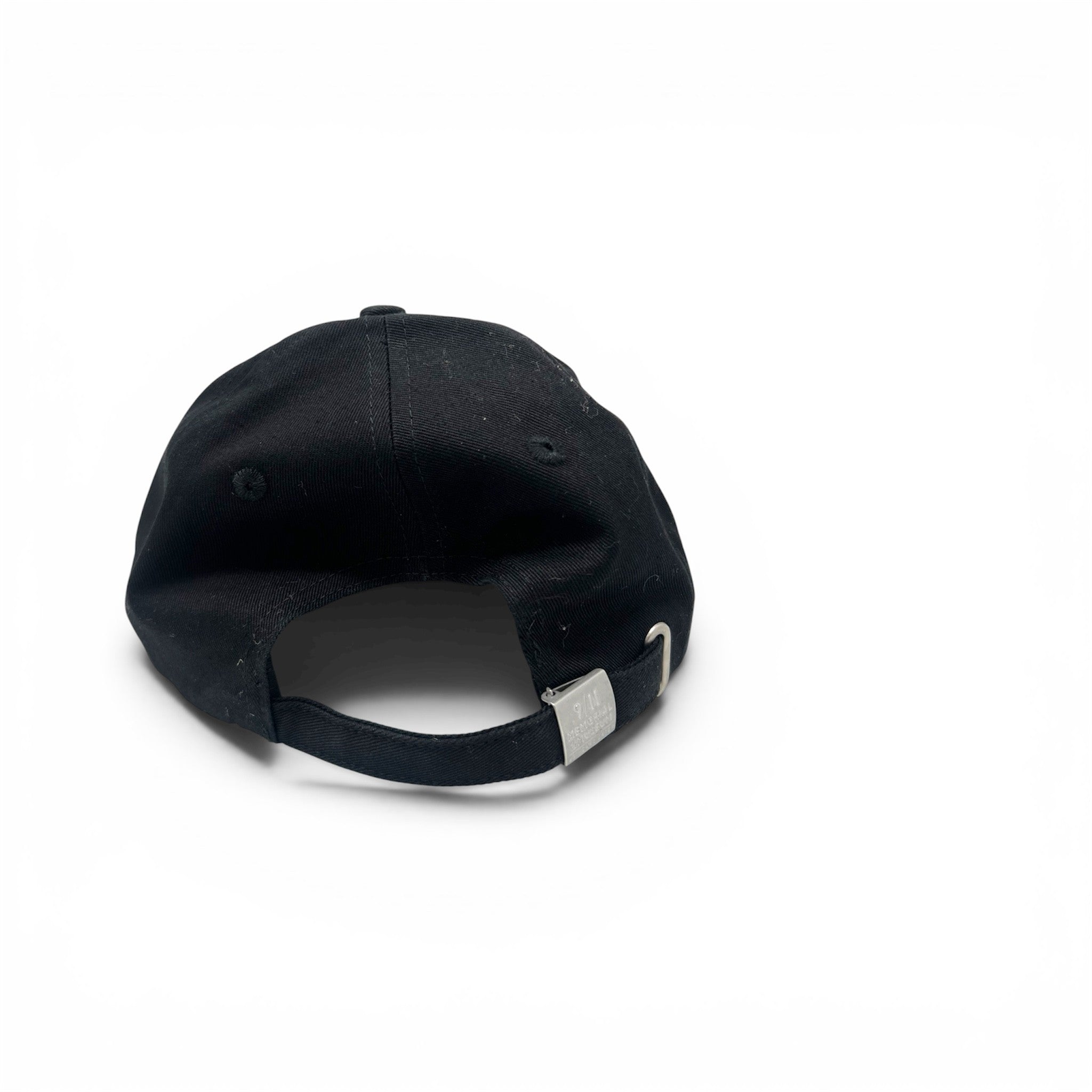 A black baseball cap shown from the back, featuring a black fabric crown, matching black eyelets, and an adjustable black strap with a silver metal slider, set against a plain white background.