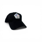 A black baseball cap with a small embroidered pentagonal patch on the front featuring an American flag and the text 'Never Forget'.