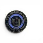 A circular commemorative challenge coin with an enamel design, featuring the text '25 YEARS STRONGER' and 'OUR RESOLVE WILL TRIUMPH!' around the border, skyscrapers and the numbers 343, 37, 23 in the center.