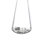 A stainless steel necklace with an engraved image of three dogs and a flag.