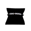 A black elastic stretch bracelet with white text 'NEW YORK', presented on a black cushion display.