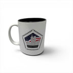 A white ceramic mug with a black interior, featuring a printed graphic on the front of the Twin Towers silhouette with an American flag background and the words 'NEVER FORGET'.