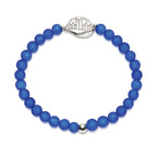 A beaded stretch bracelet made of matte royal blue beads, featuring a silver-toned metal NEVER FORGET medallion and a small silver accent bead, shown on a plain white background.