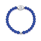 A beaded stretch bracelet made of matte royal blue beads with a polished silver-toned oval centerpiece engraved with 'NYC 9-11-2001 9-11-2026 25', shown on a plain white background.