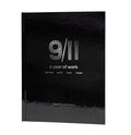 This image features the hardcover book titled "9/11: A Year of Work" by Anthony Graviano. The cover is a striking black, with minimalistic white and grey text and graphics that evoke a sense of somber reflection.