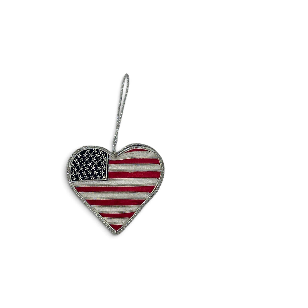A heart-shaped hanging ornament featuring a distressed American flag design with red and white stripes and a navy star field, outlined in silver and suspended by a silver loop.