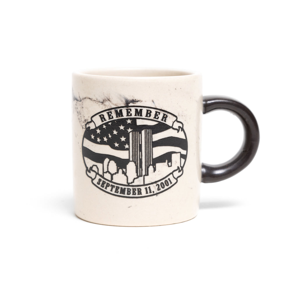 A beige ceramic mini mug with a marble-like pattern and 'REMEMBER 9/11' printed on it, featuring an American flag design.