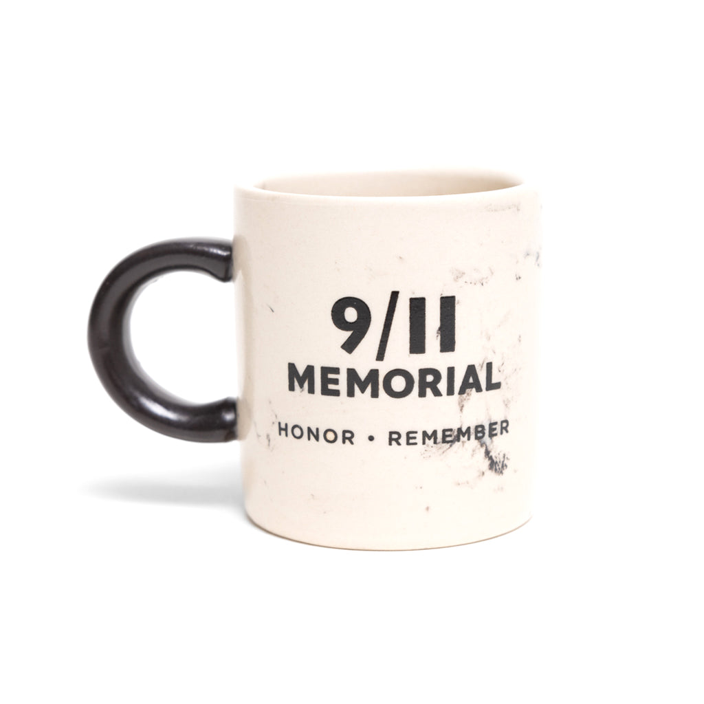 A beige ceramic mini mug with a marble-like pattern and '9/11 MEMORIAL HONOR REMEMBER' on it