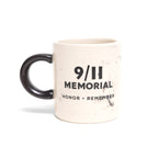 A beige ceramic mini mug with a marble-like pattern and '9/11 MEMORIAL HONOR REMEMBER' on it
