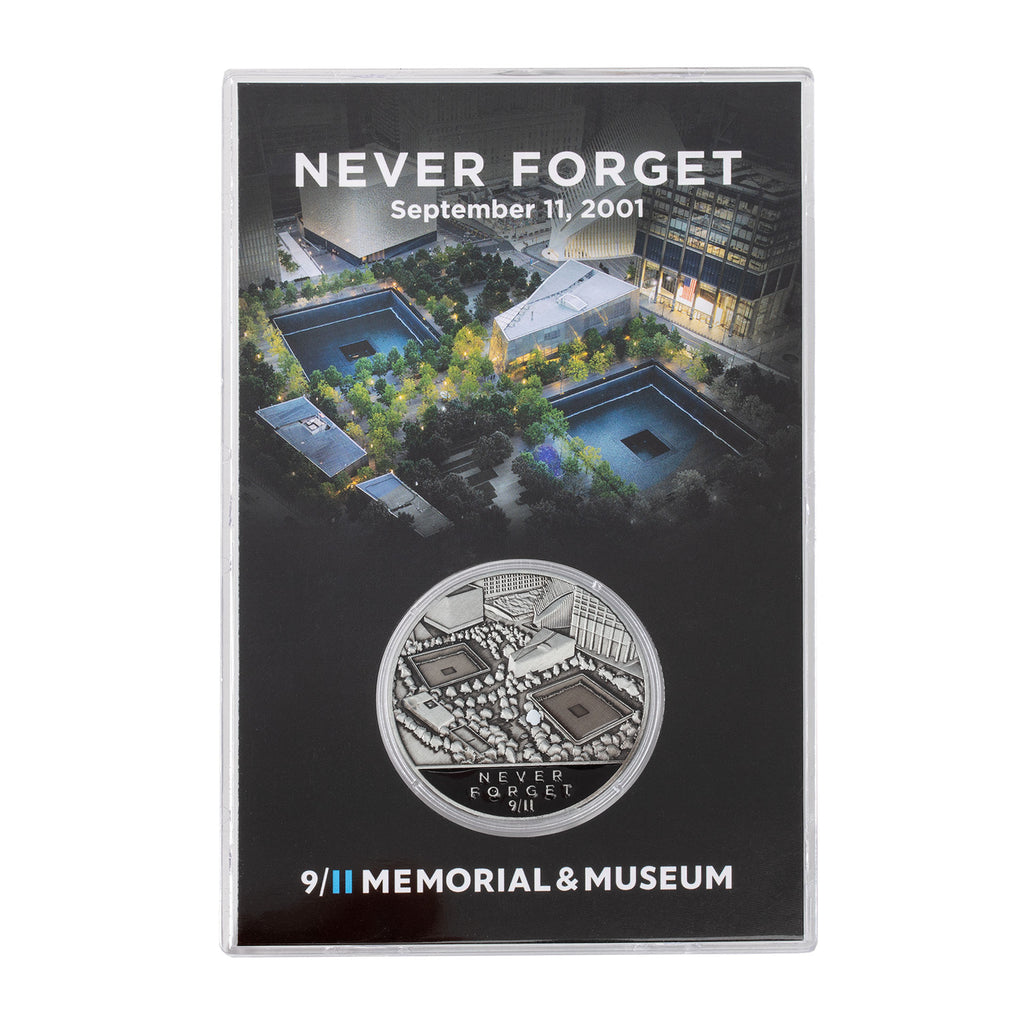 A collectible coin in a case, with the inscription 'NEVER FORGET September 11, 2001' and the logo of the 9/11 Memorial & Museum.