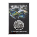 A collectible coin in a case, with the inscription 'NEVER FORGET September 11, 2001' and the logo of the 9/11 Memorial & Museum.