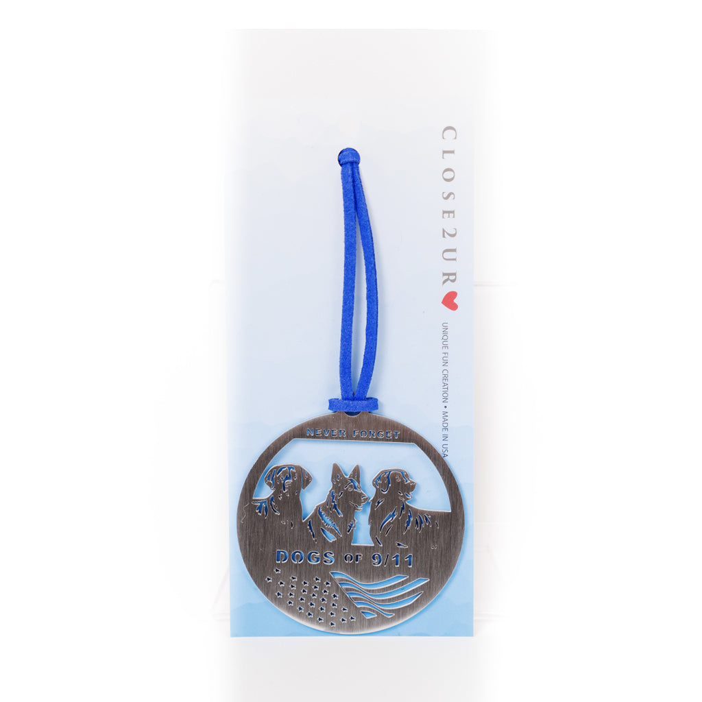 A stainless steel circular keepsake with an engraved image of three dogs and a flag with a blue ribbon attached on a white to blue omber card backer.
