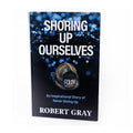 A book cover for 'Shoring Up Ourselves: An Inspirational Story of Never Giving Up' by Robert Gray, featuring a black background with blue speckles and an image of a fire helmet.