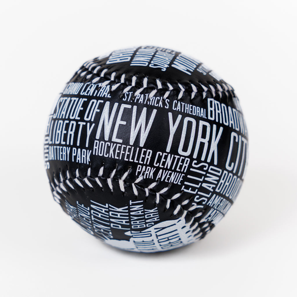 A black baseball with New York City landmarks and streets printed in white lettering on a white background.