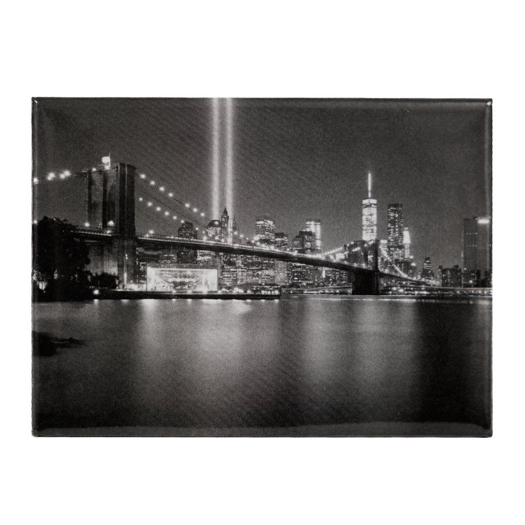 Black and white photo of a city skyline with a bridge at night.
