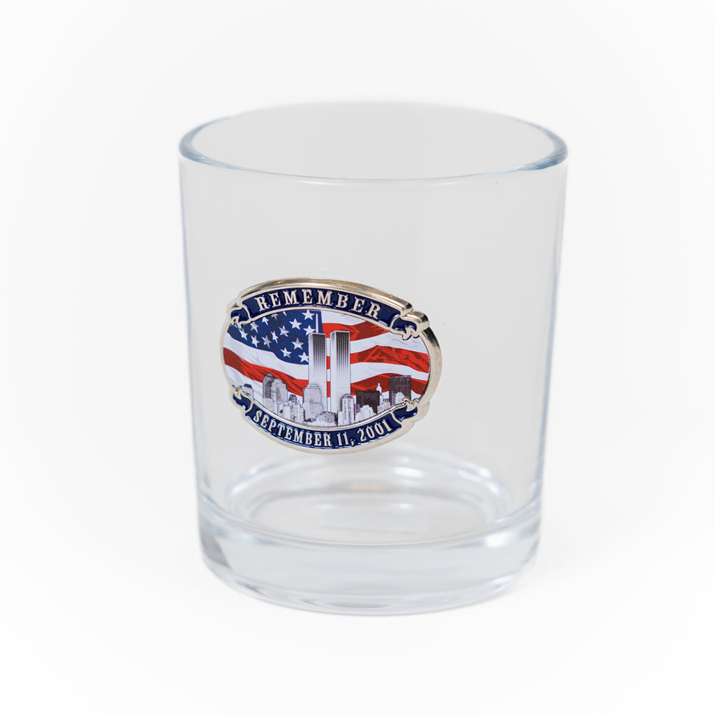 A clear water glass with a logo remembering the Twin Towers and featuring an American flag.