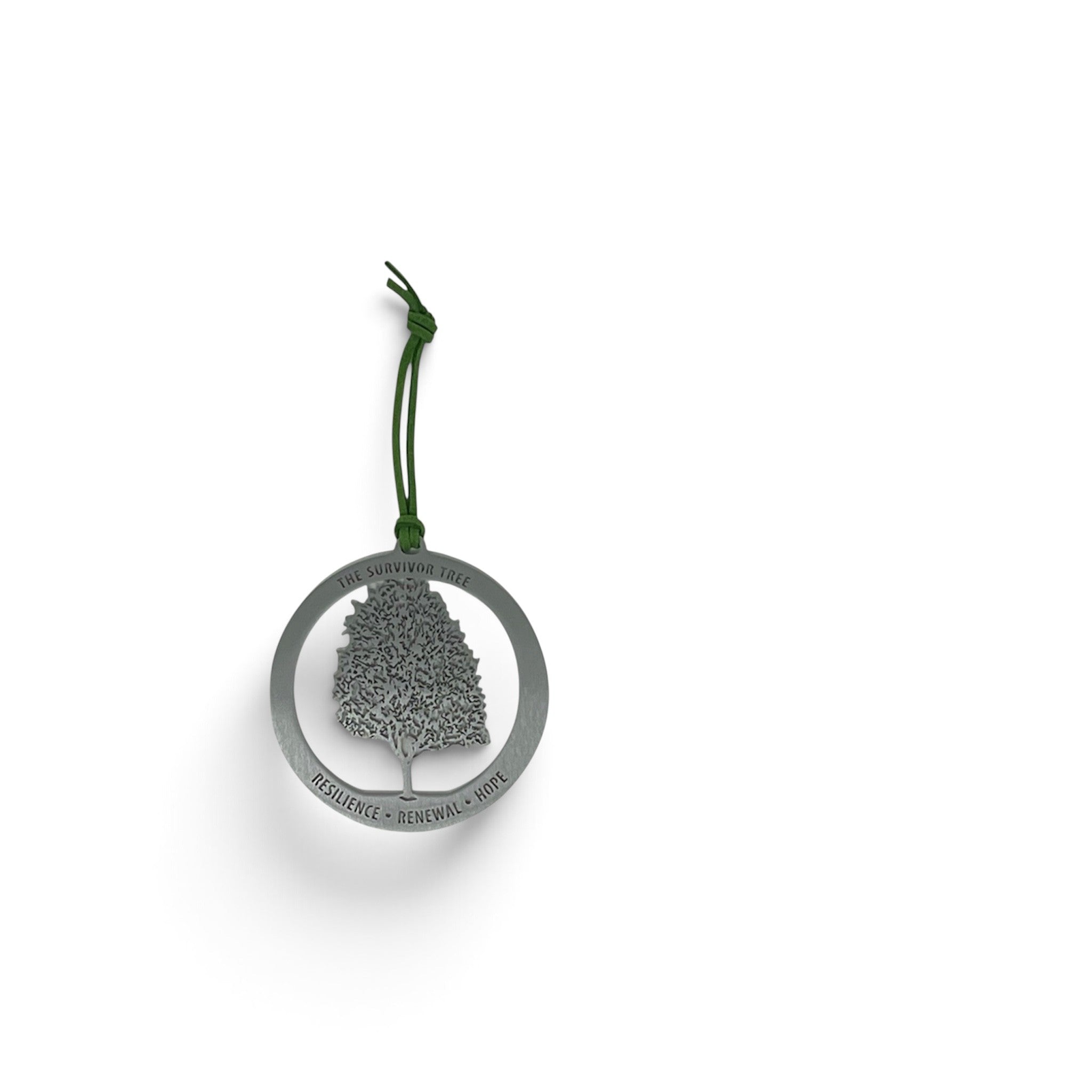 A silver metal keepsake featuring a tree silhouette inside a circular frame with the words RESILIENCE • RENEWAL • Hope engraved along the bottom edge, hanging from a dark green cord on a white background.