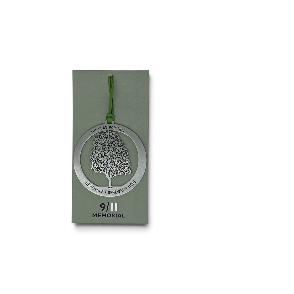 A silver metal memorial tree ornament with a green hanging string, displayed on its olive green card packaging against a white background.