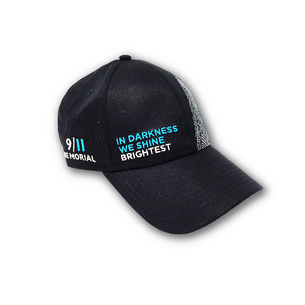 A black cap with a white graphic of the Twin Towers and the words 'In Darkness We Shine Brightest' on it.