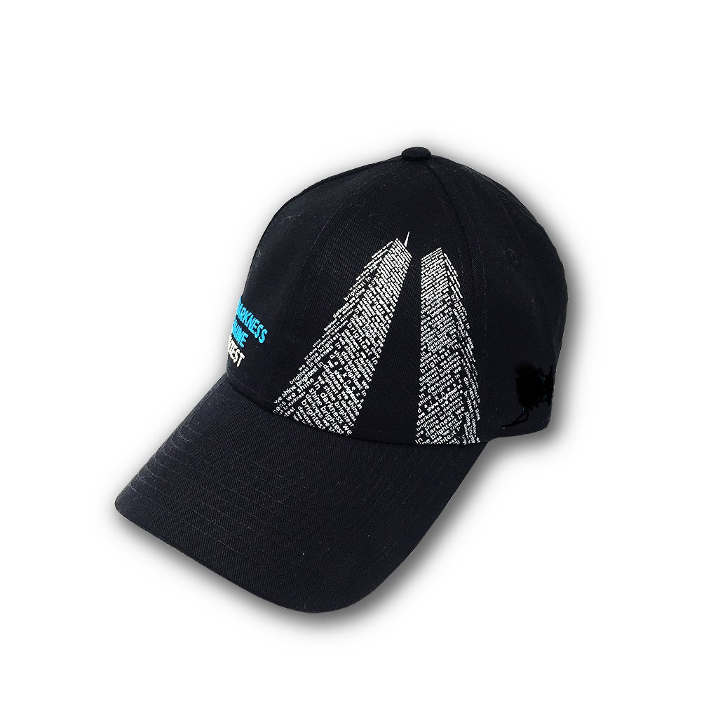 A black cap with a white graphic of the Twin Towers and the words 'In Darkness We Shine Brightest' on it.