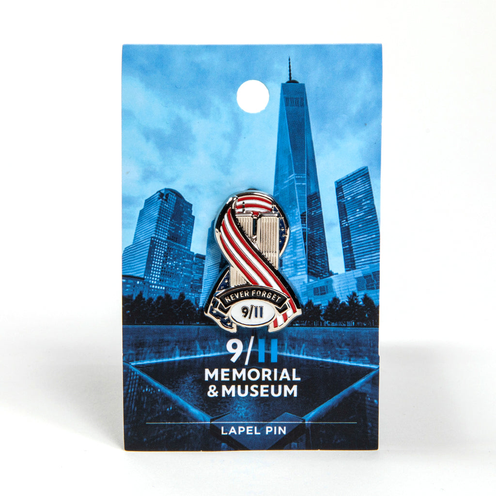 A metal die-cut ribbon lapel pin with a patriotic design featuring an American flag and the text 'Never Forget 9/11' on a blue card backer.