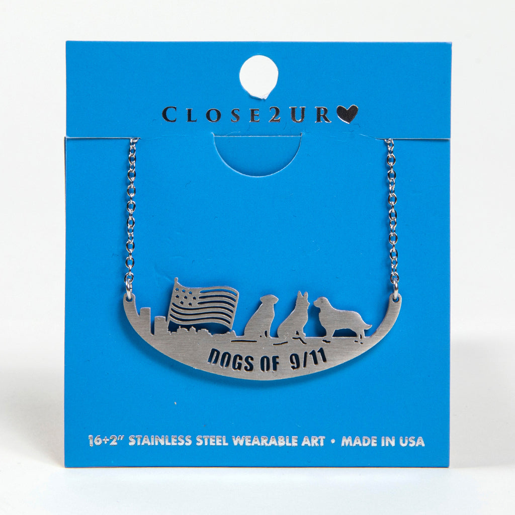 A stainless steel necklace with an engraved image of three dogs and a flag on a blue card backer.
