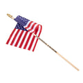 An American flag with a wooden pole and a label that reads '9/11 MEMORIAL & MUSEUM'.
