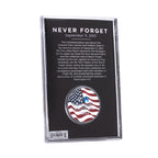 A commemorative coin with a US flag and Twin Towers design, housed in a clear display case, with 'NEVER FORGET' text on the case.