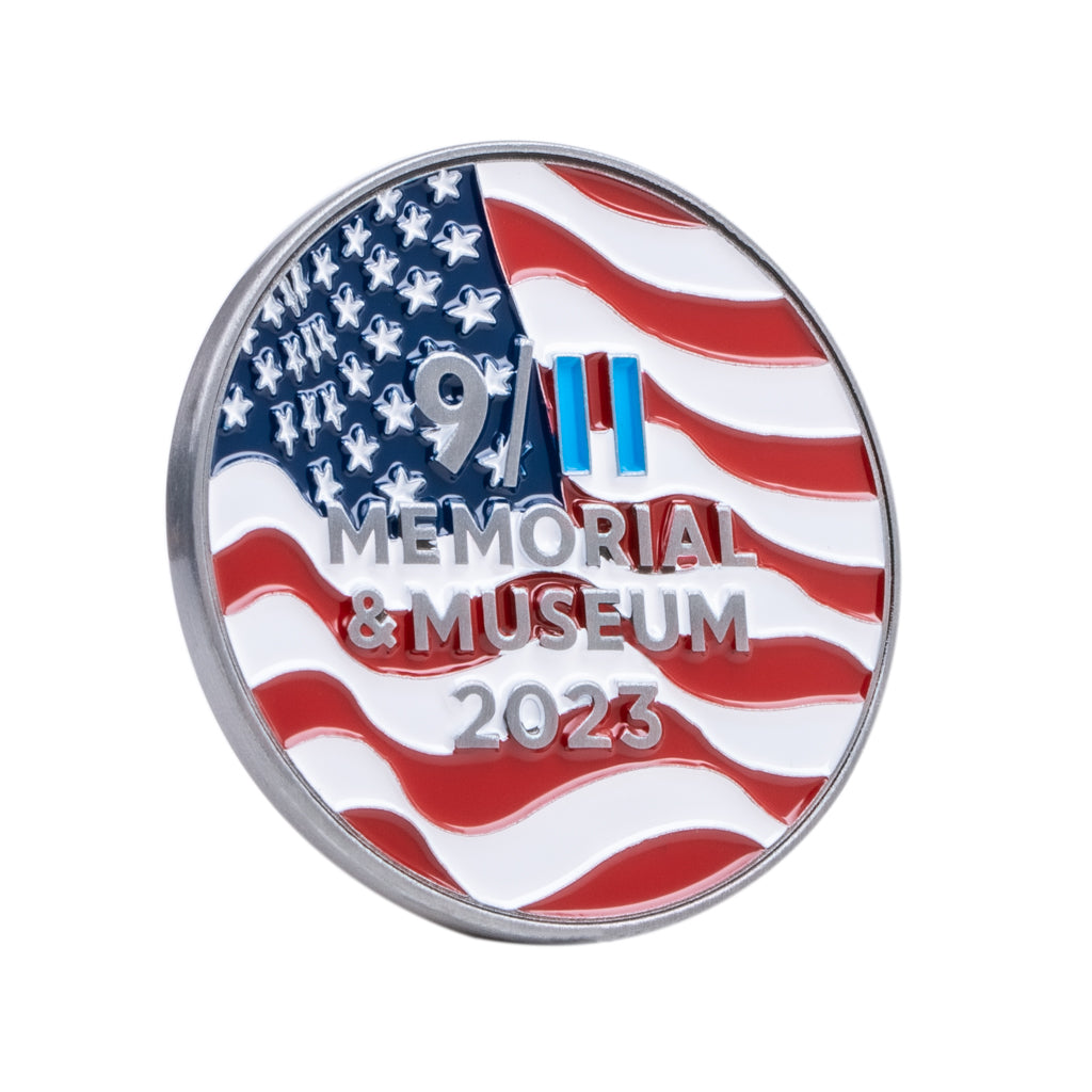 The back of a commemorative coin featuring wavy stars and stripes and the 9/11 Memorial & Museum logo.