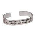 A metal bracelet with text engraved on it, including '343 FDNY 37 PAPD 23 NYPD - ALL GAVE SOME - SOME GAVE ALL'.