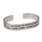 A metal bracelet with text engraved on it, including '343 FDNY 37 PAPD 23 NYPD - ALL GAVE SOME - SOME GAVE ALL'.