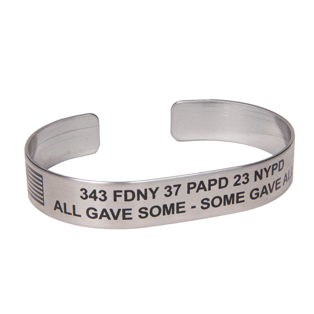 A metal bracelet with text engraved on it, including '343 FDNY 37 PAPD 23 NYPD - ALL GAVE SOME - SOME GAVE ALL'.