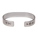 A metal bracelet with text engraved on the back saying WTC and 9-11-01.